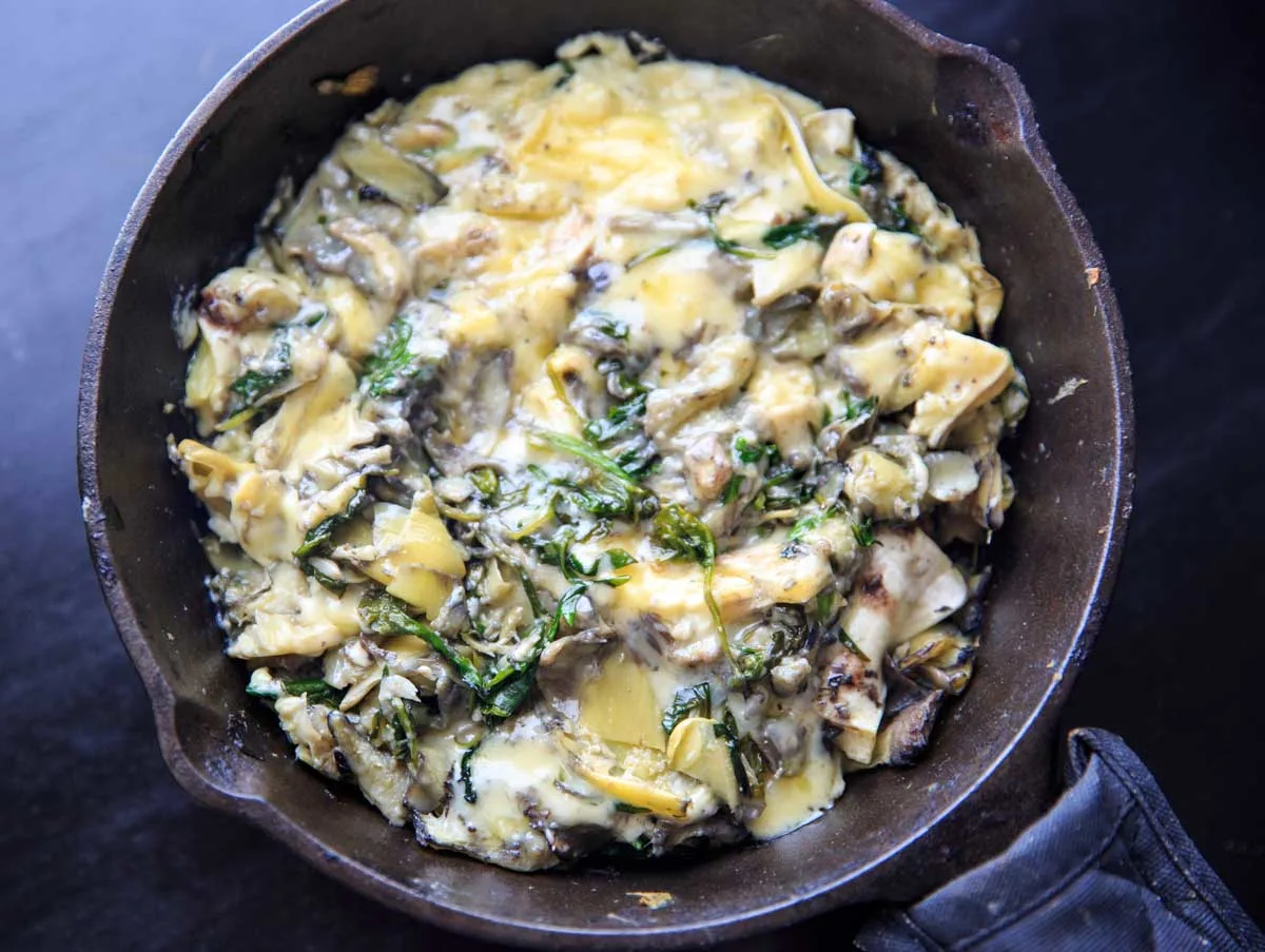 Arugula (or spinach) and artichoke brie dip, made in a cast iron skillet. A delicious and unique appetizer!