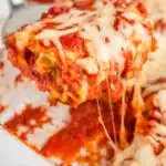 cheese pull picture of serving one lasagna roll up out of the casserole dish