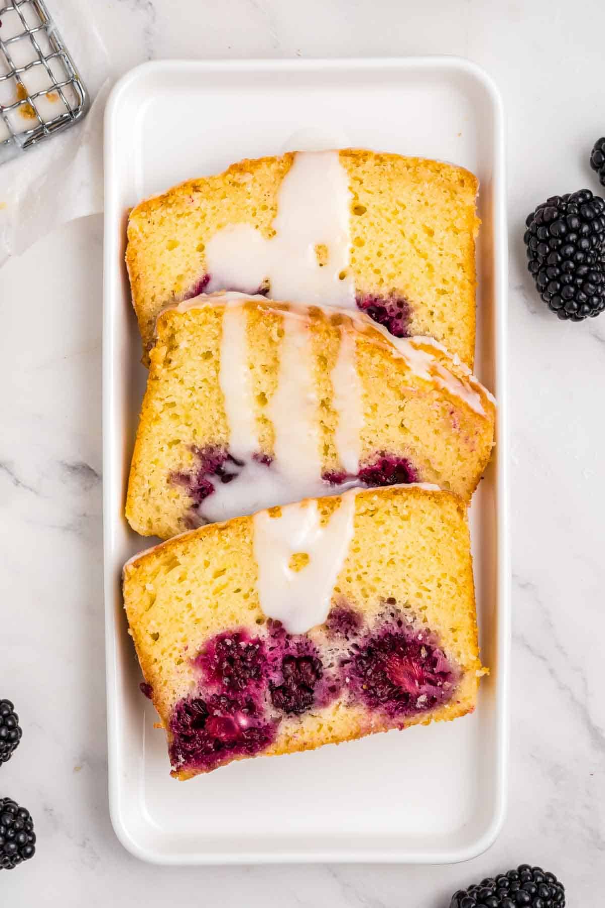 3 pieces of lemon blackberry bread with glaze drizzled over it