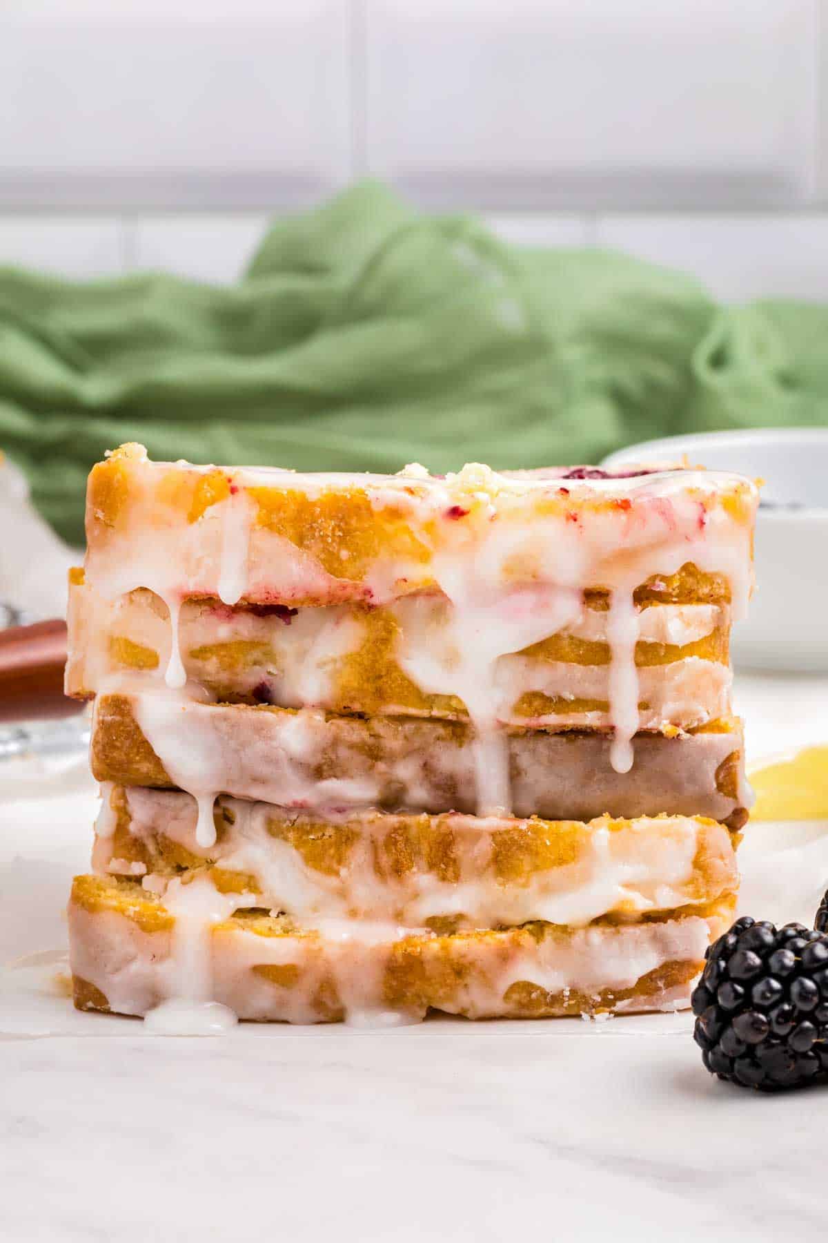 stack of sliced lemon blackberry bread with glaze drizzled over top