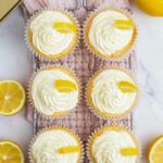 6 lemon cupcakes with frosting and wedges of lemon