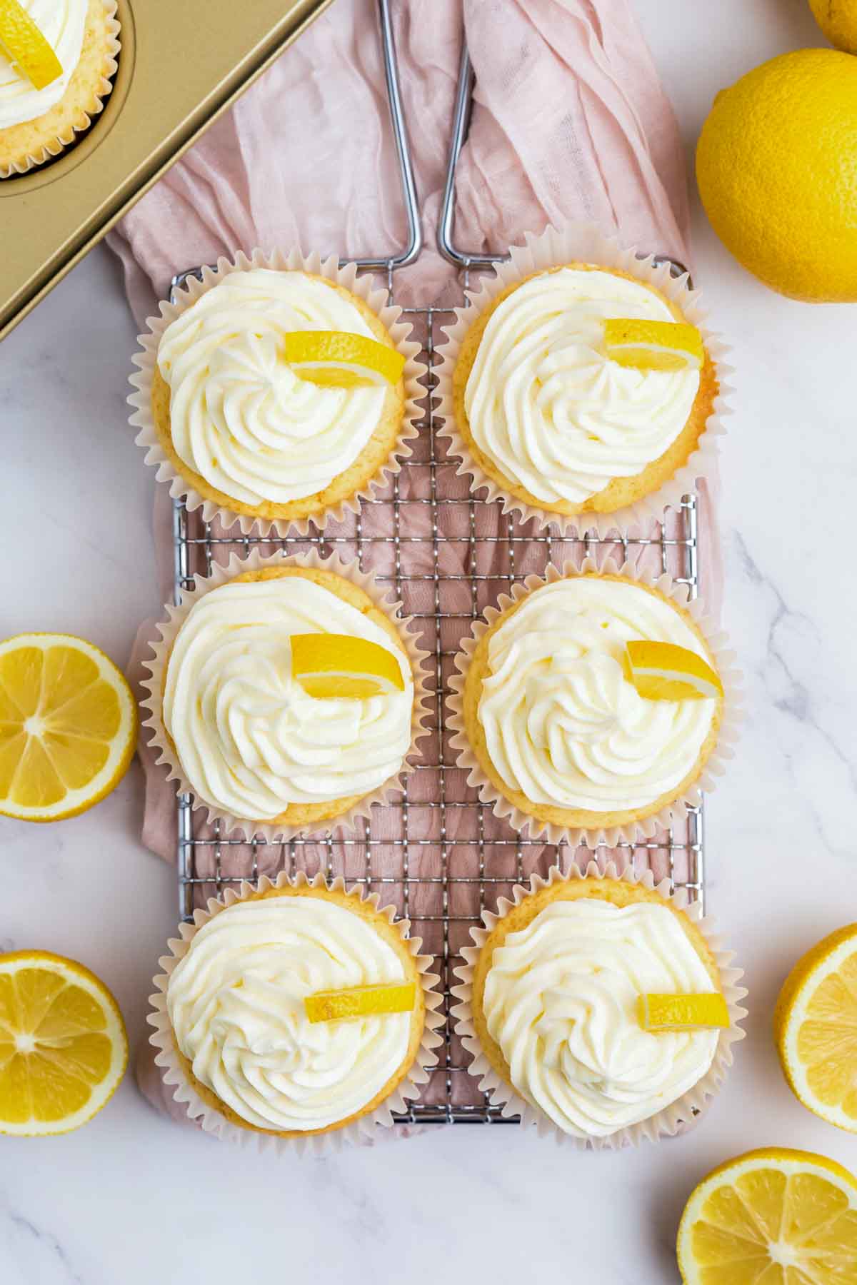 6 lemon cupcakes with frosting and wedges of lemon