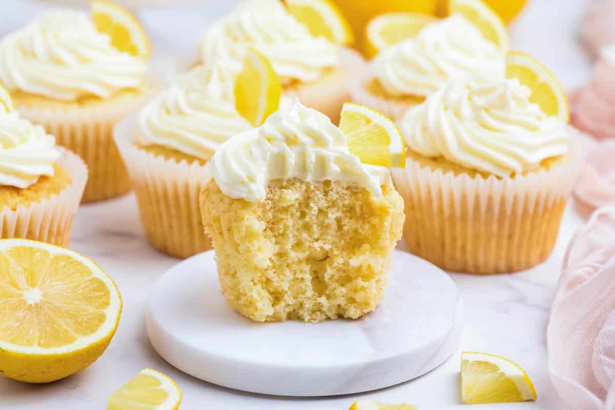 lemon cupcake with buttercream frosting with a bite taken out so you can see the moist inside