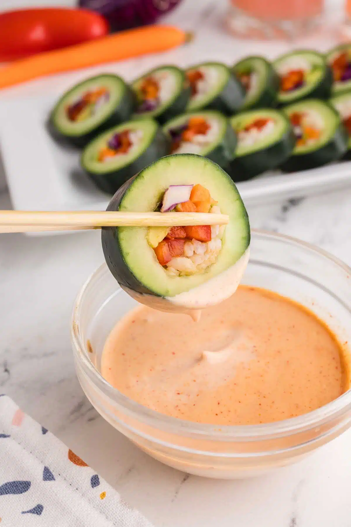 dipping cucumber sushi into spicy mayo sauce