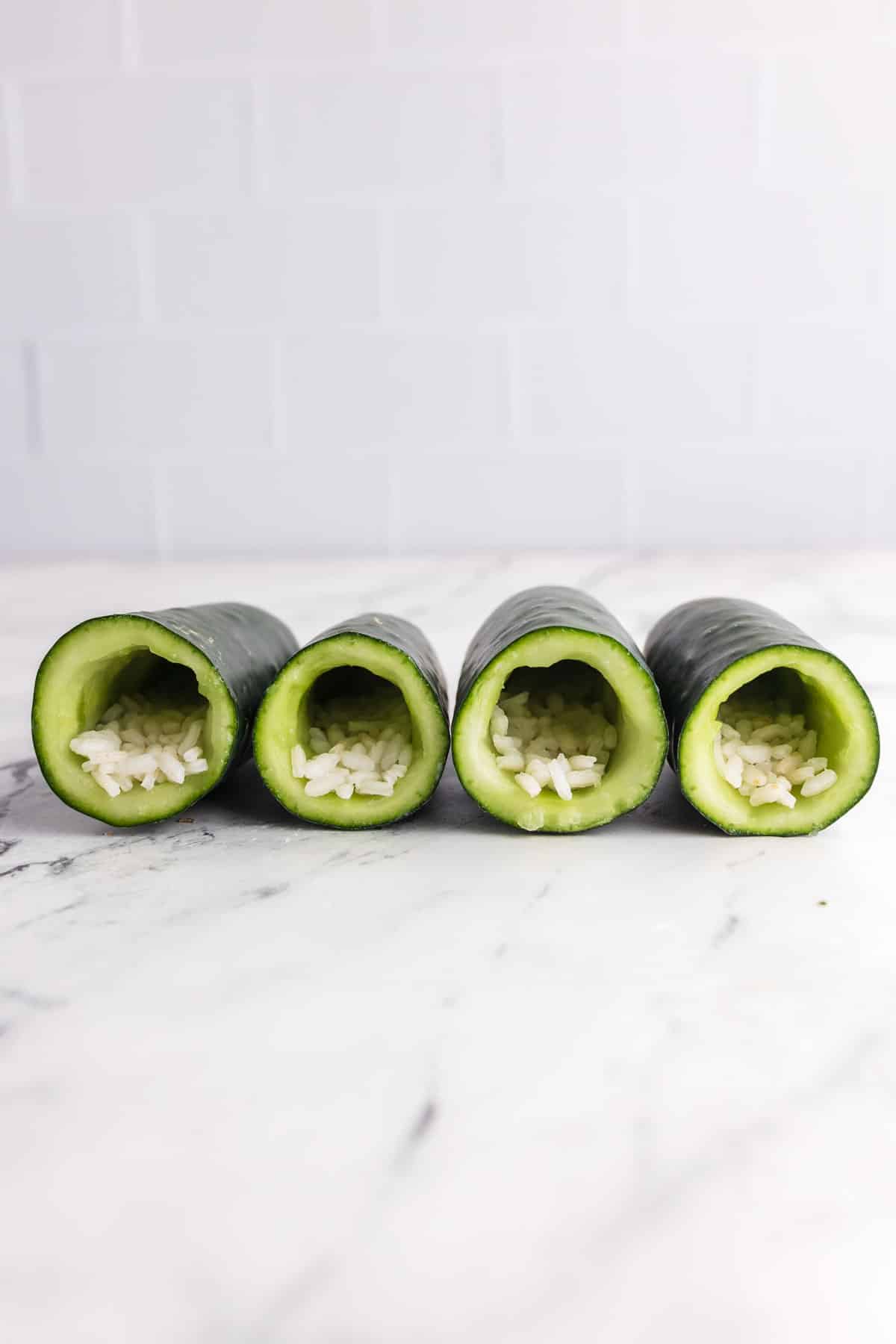 four halves of hollowed out cucumber with sushi rice