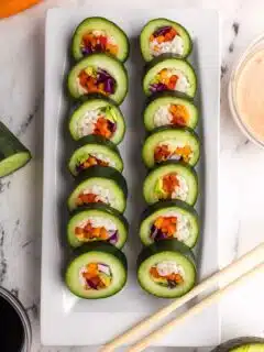 14 prepared pieces of stuffed cucumber sushi on a white serving plate