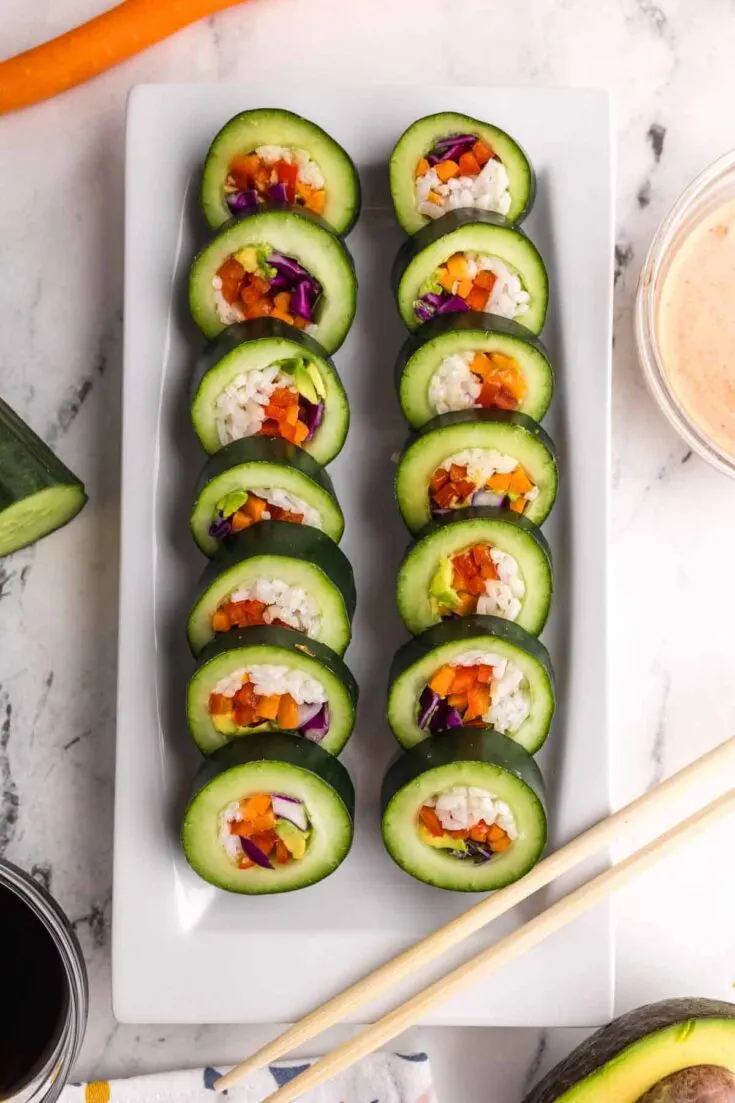 14 prepared pieces of stuffed cucumber sushi on a white serving plate