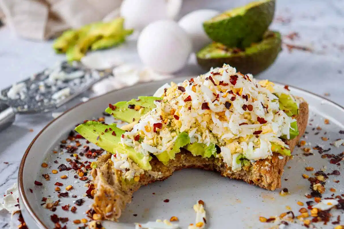 grated hard boiled egg on top of avocado toast half eaten