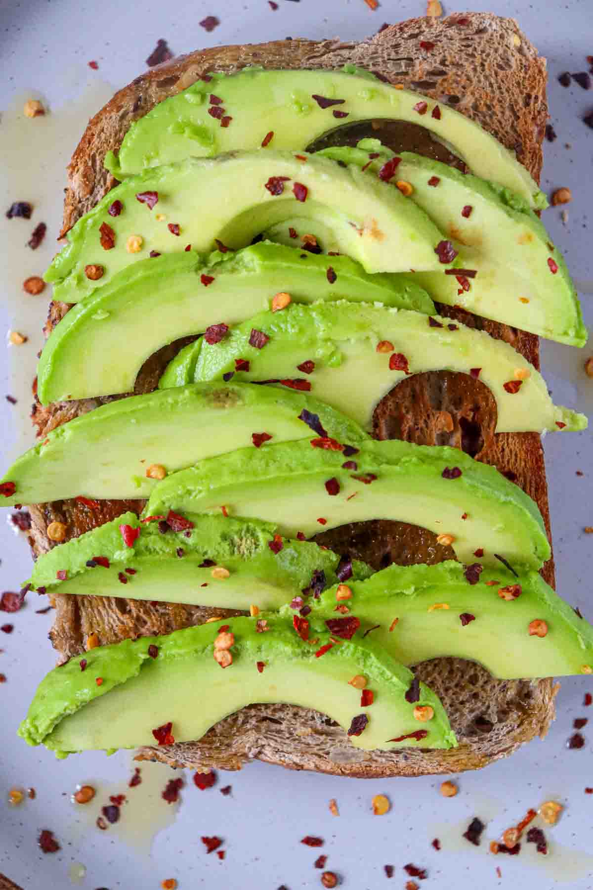 slices of avocado on a piece of toast with red chili flakes sprinkled on top, close up