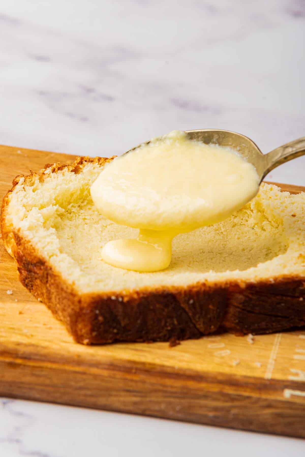 spoon pouring yogurt custard on top of piece of bread