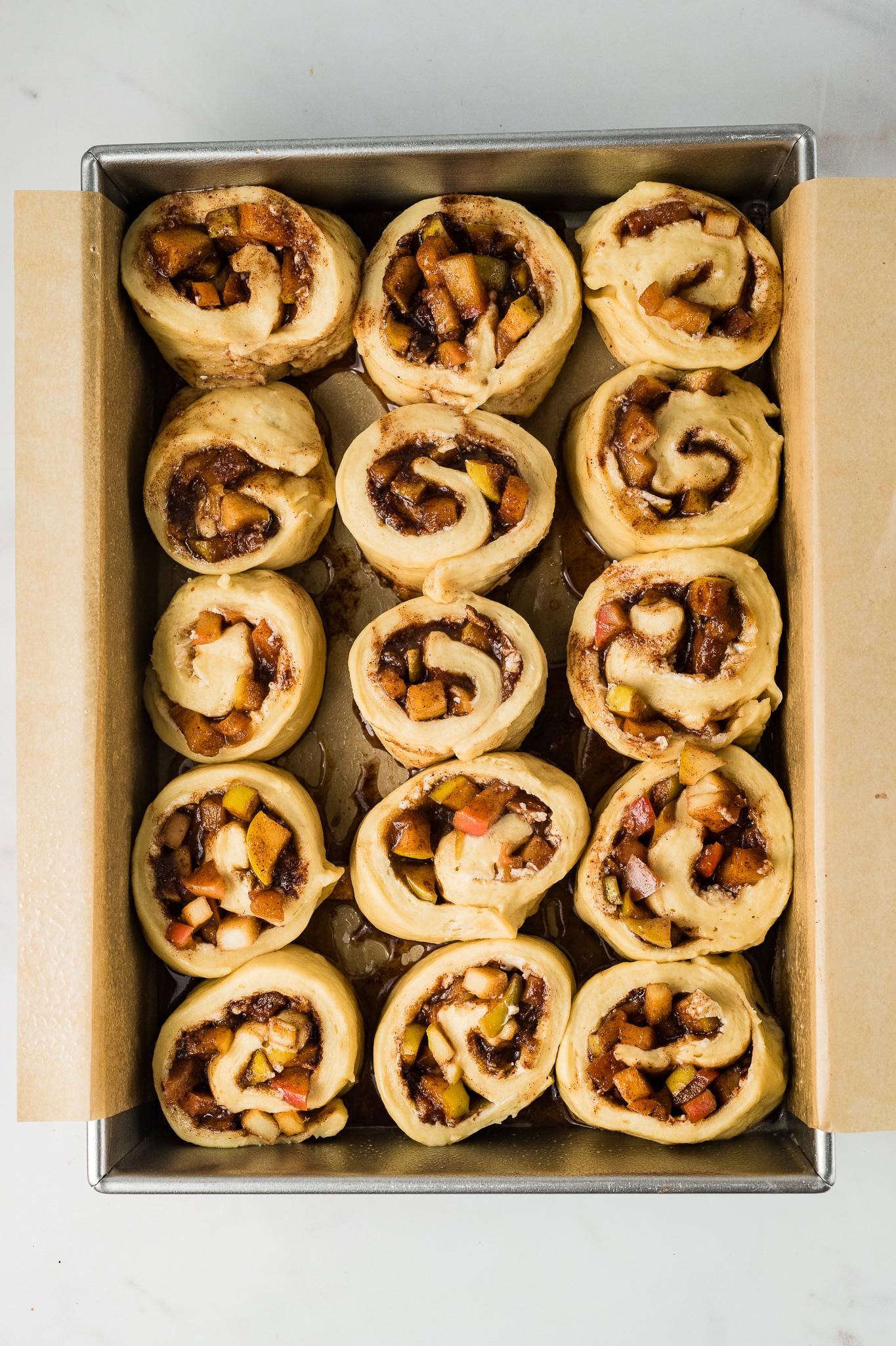 15 individual apple cinnamon rolls before baking on parchment lined baking sheet