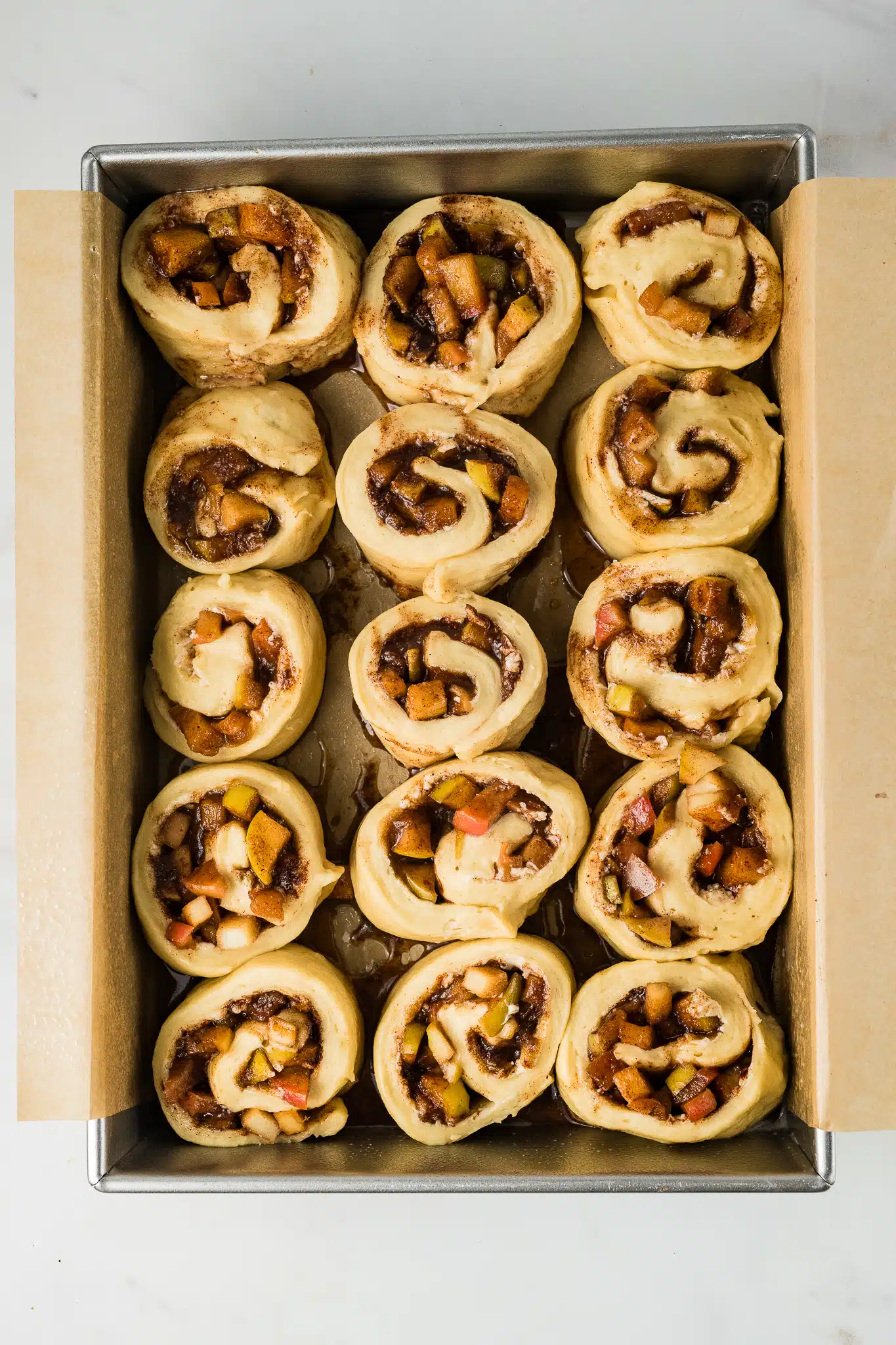 15 individual apple cinnamon rolls before baking on parchment lined baking sheet