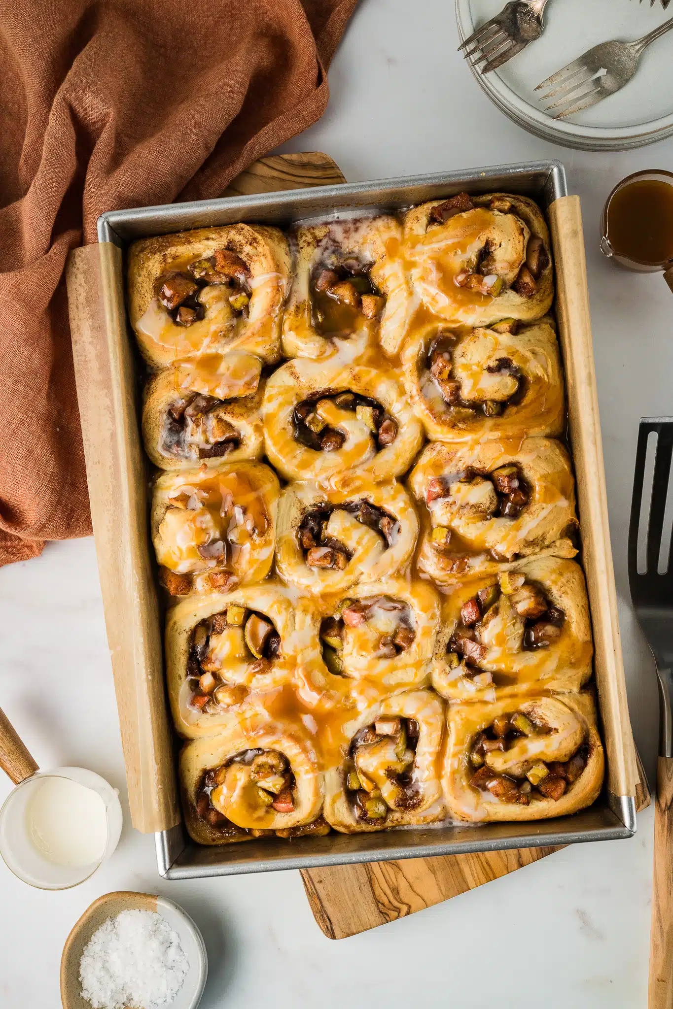 15 individual apple cinnamon rolls after baking on parchment lined baking sheet