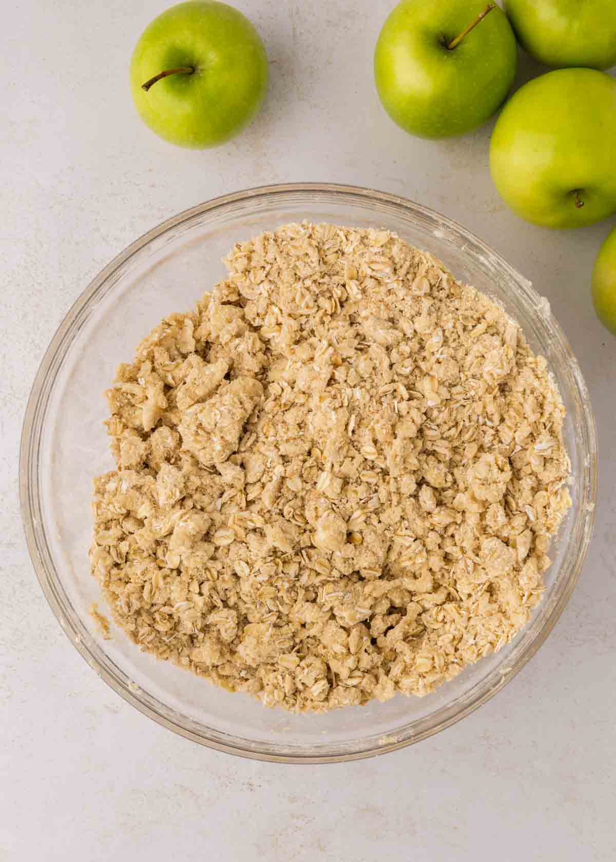 topping for apple crisp in a bowl with green apples in background