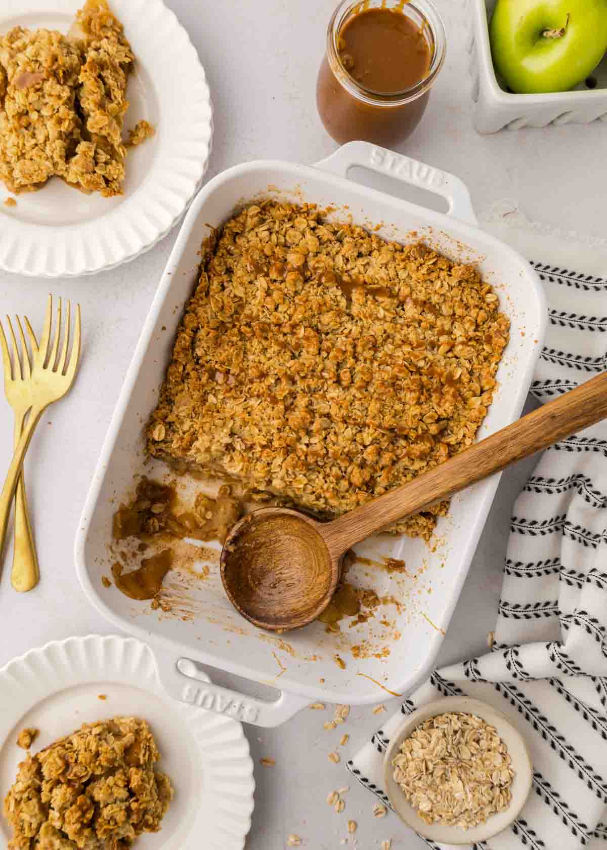 caramel apple crisp in baking dish half gone with serving spoon resting