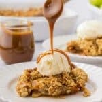 drizzling caramel sauce over top a piece of caramel apple crisp