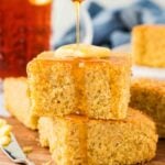 drizzling honey over 2 pieces of gluten-free cornbread on brown serving plate