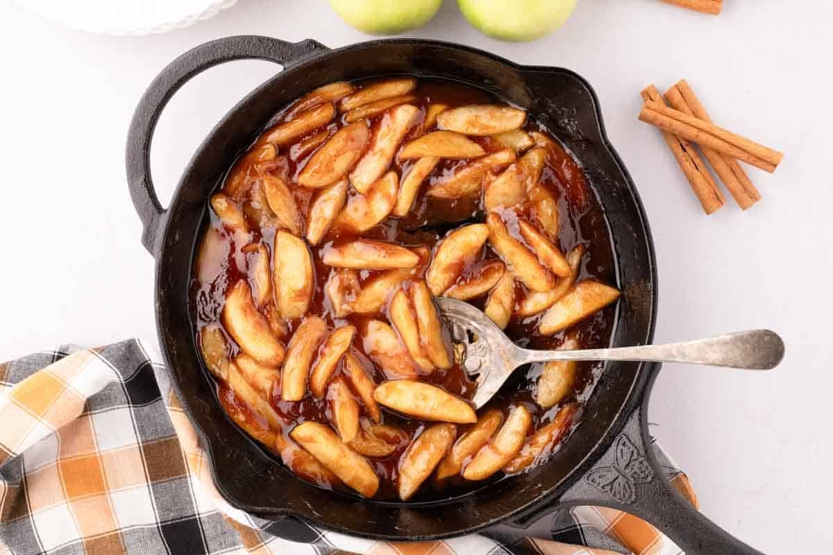 southern fried apples in a large skillet with a serving spoon