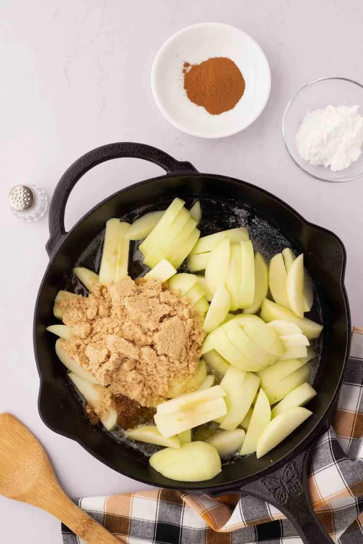 sliced green apples in a skillet with melted butter and brown sugar