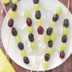 5 skewers of Grape tanghulu on white plate