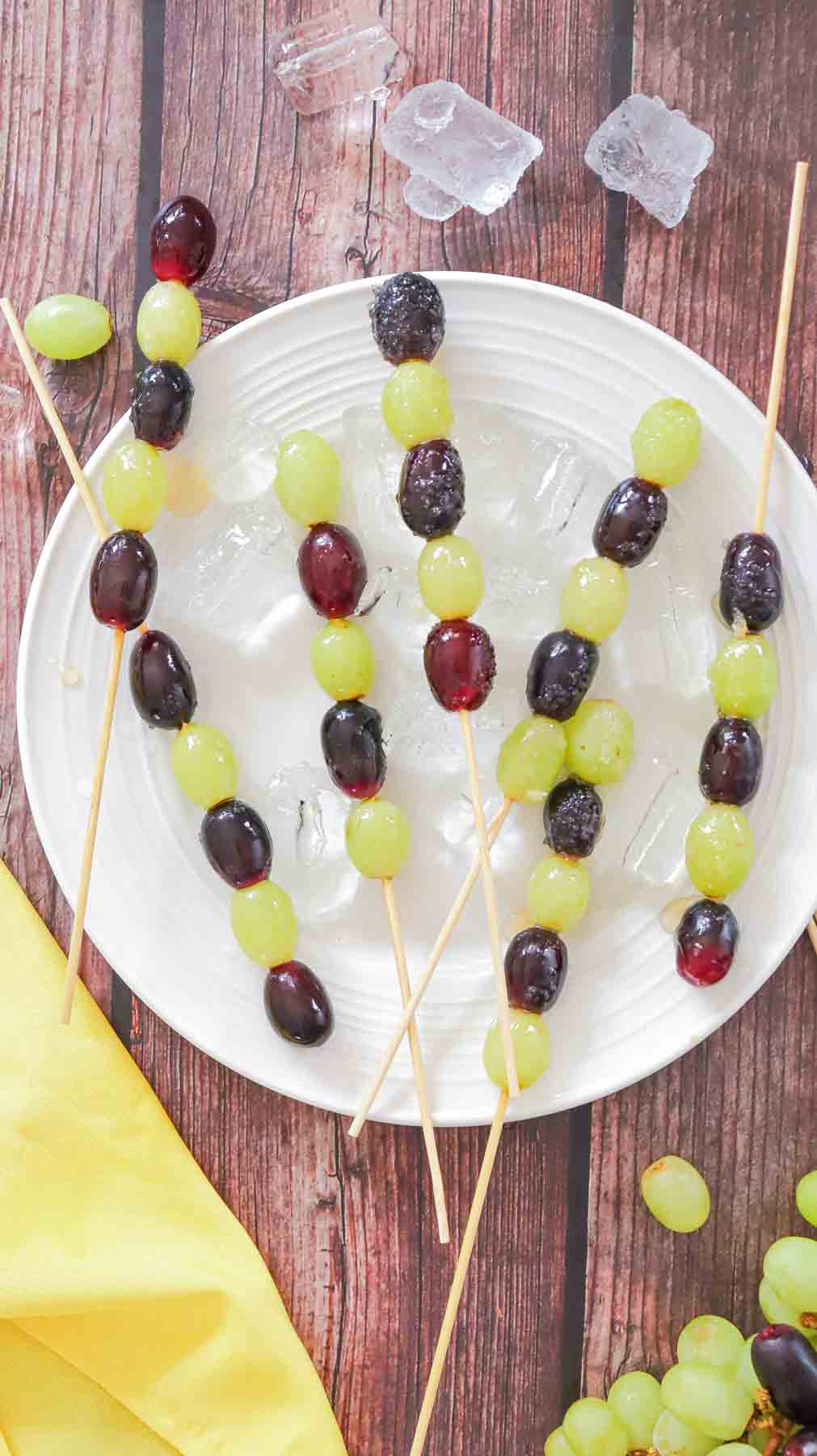 5 skewers of Grape tanghulu on white plate