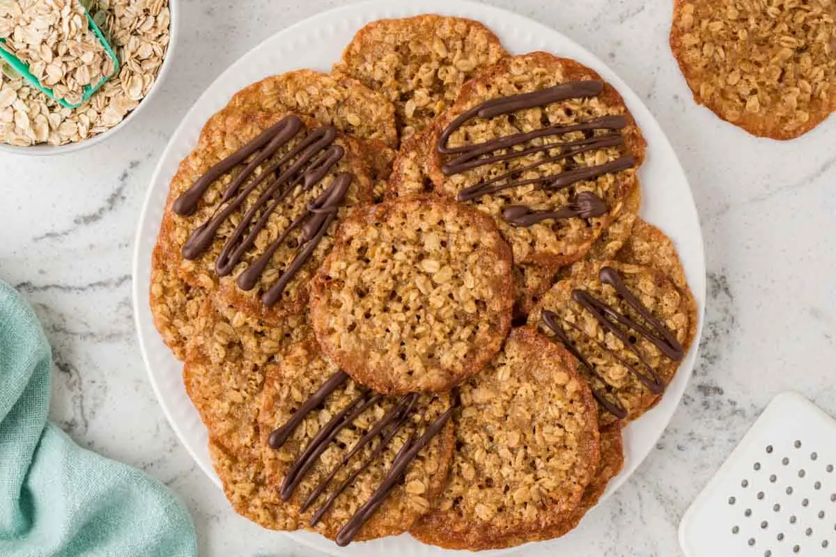 a white plate full of oatmeal lace cookies