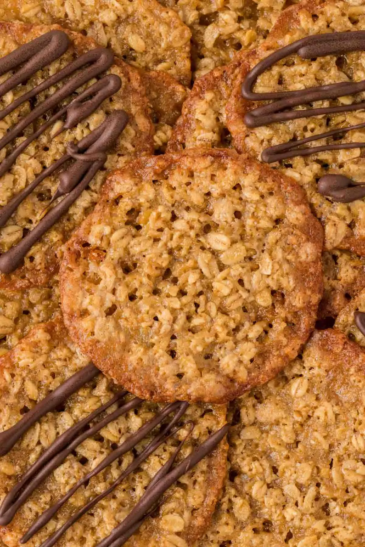 a pile of oatmeal lace cookies with a few with chocolate drizzle