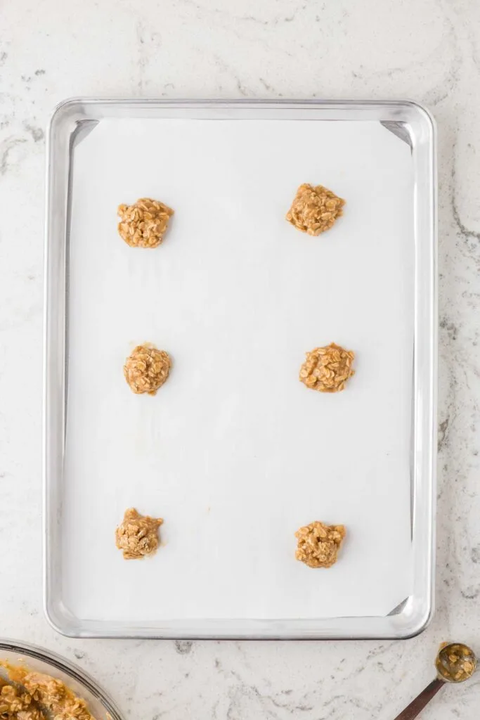 dough of oatmeal lace cookies in 6 small balls on parchment lined baking sheet