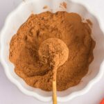 homemade pumpkin pie spice mixed up in white bowl with spoon full in center