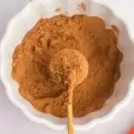 homemade pumpkin pie spice mixed up in white bowl with spoon full in center