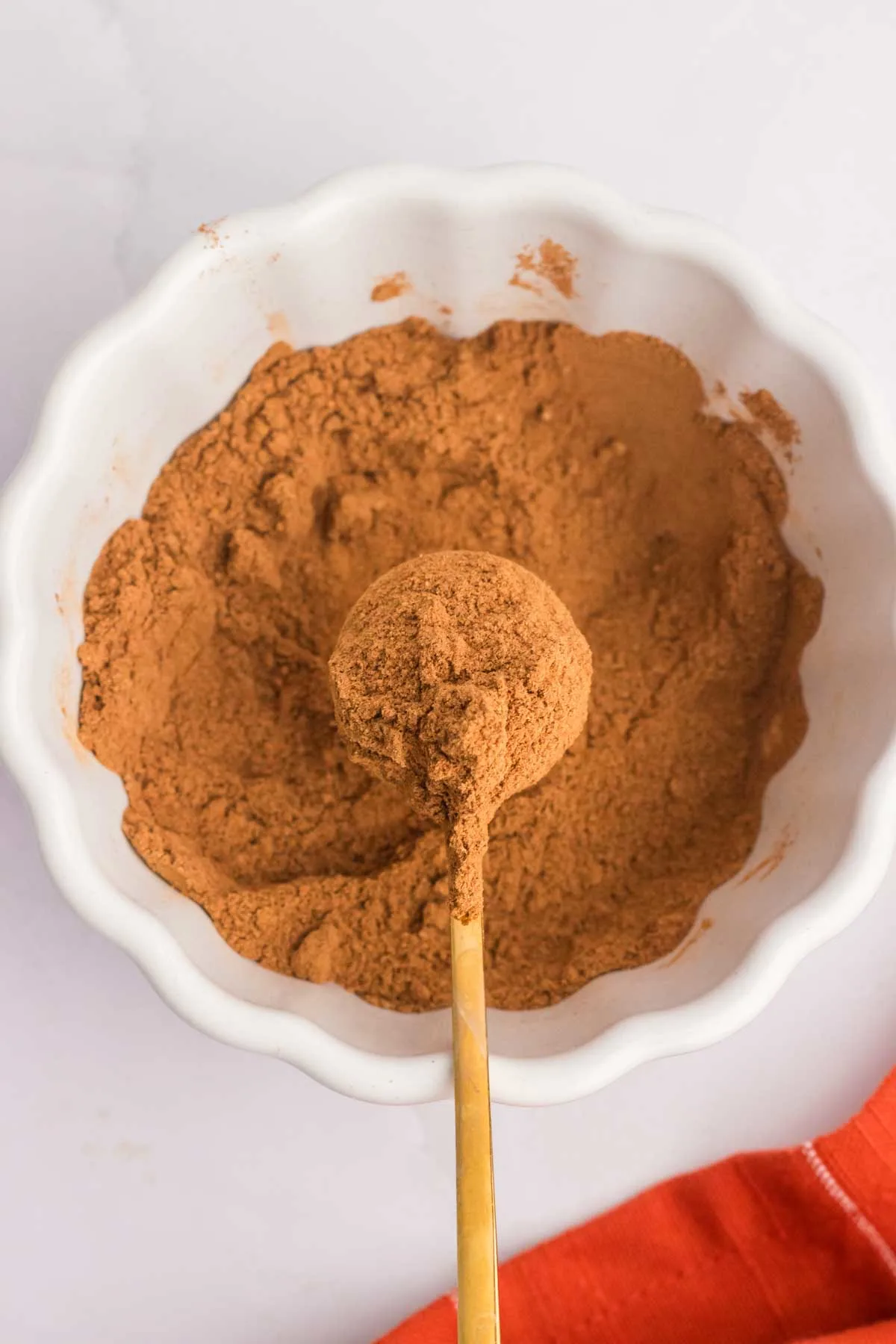 homemade pumpkin pie spice mixed up in white bowl with spoon full in center