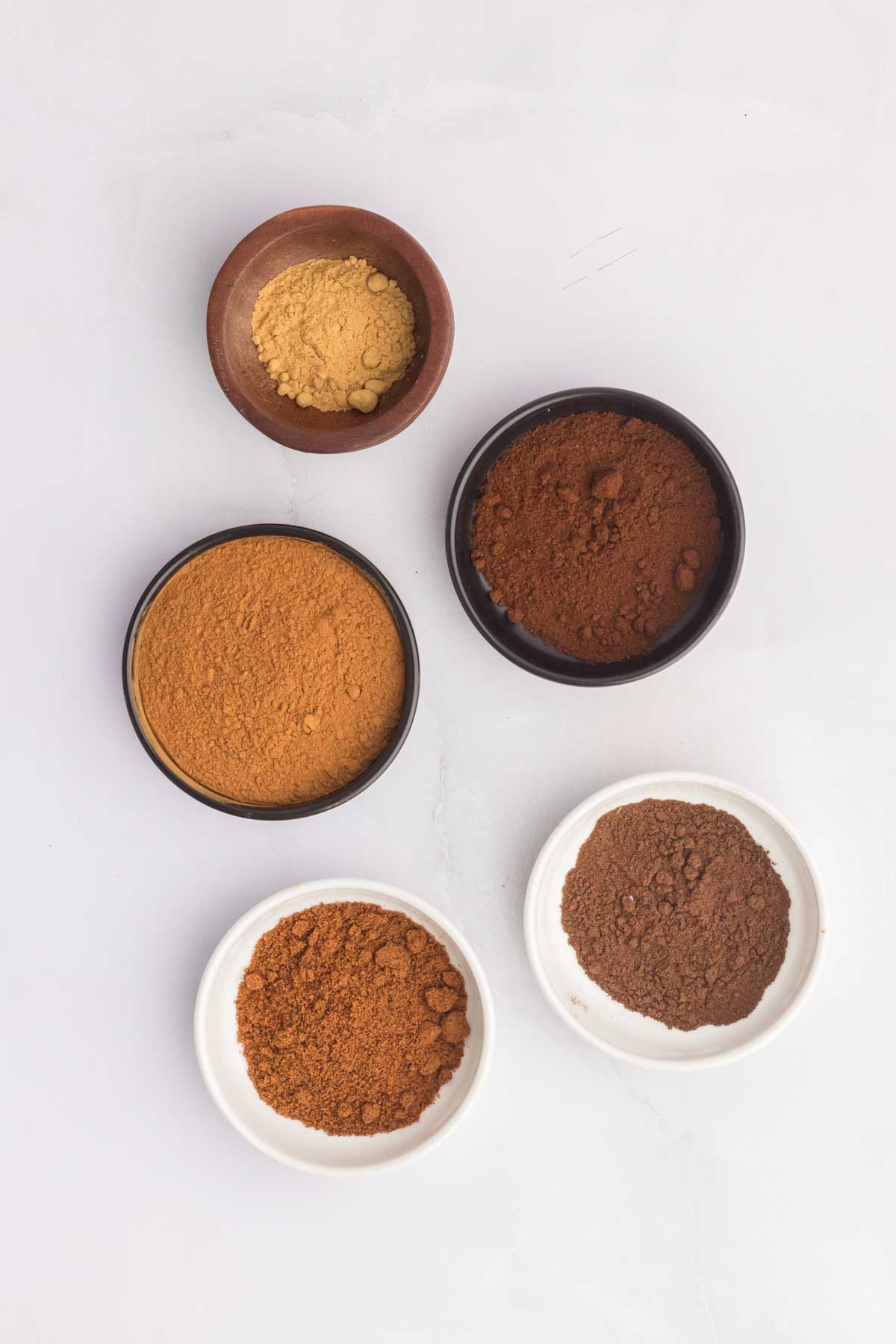 5 individual ingredients used to make pumpkin pie spice in separate bowls