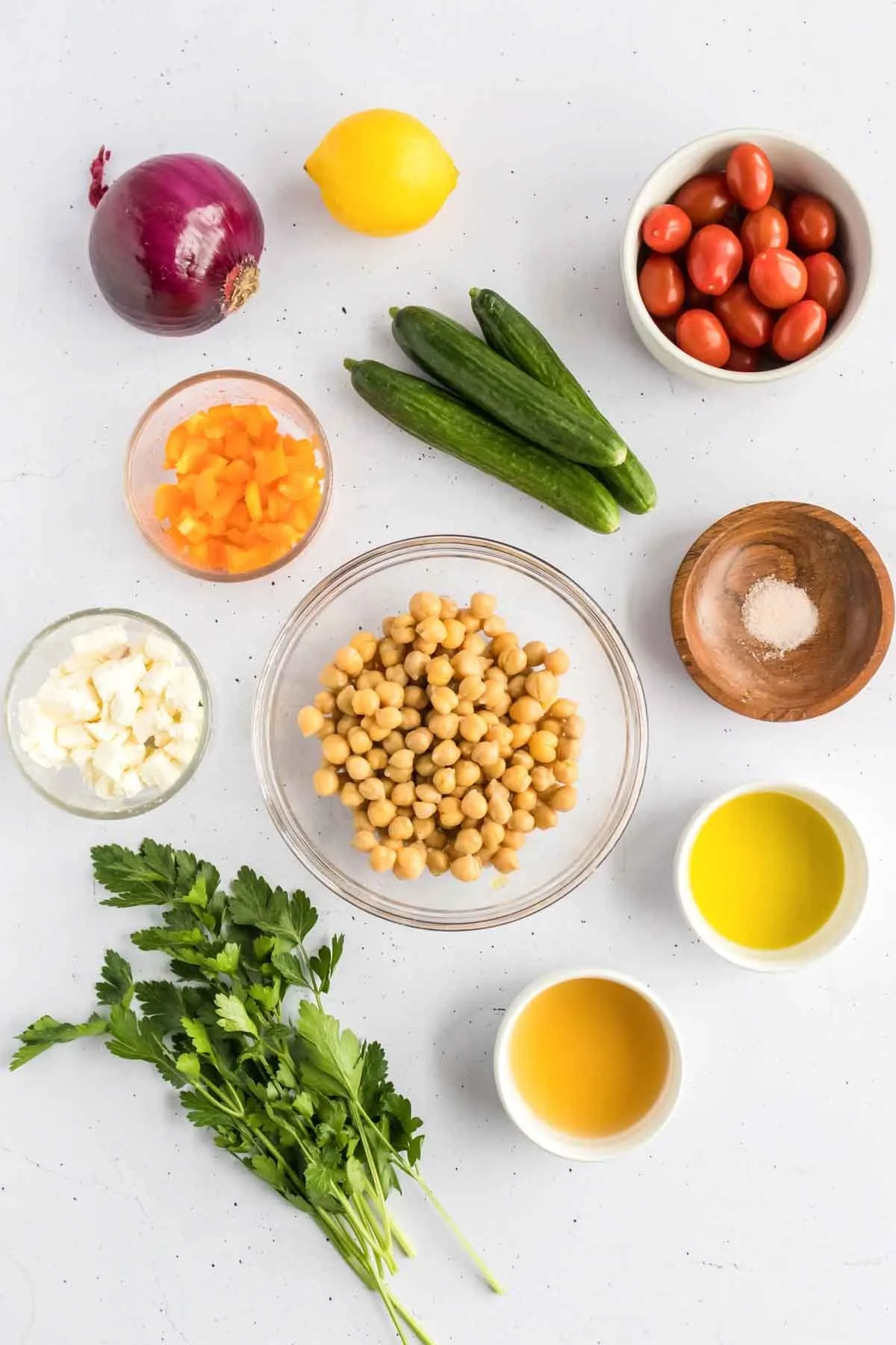 individual ingredients for cucumber chickpea salad in individual bowls, overhead shot of 11 ingredients