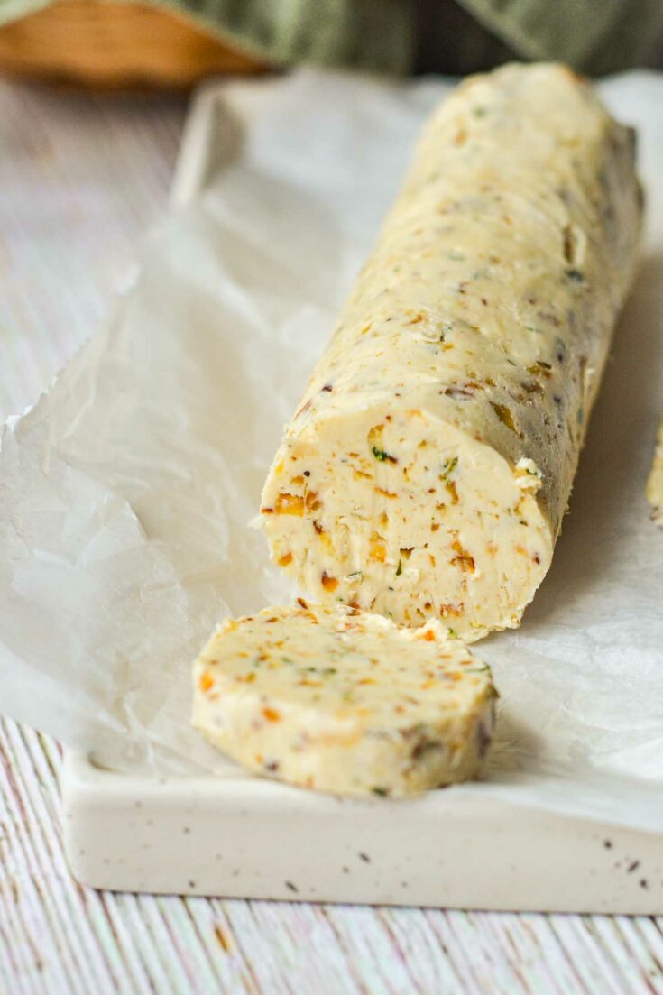 roll of French onion compound butter with a slab cut off the front, on wax paper