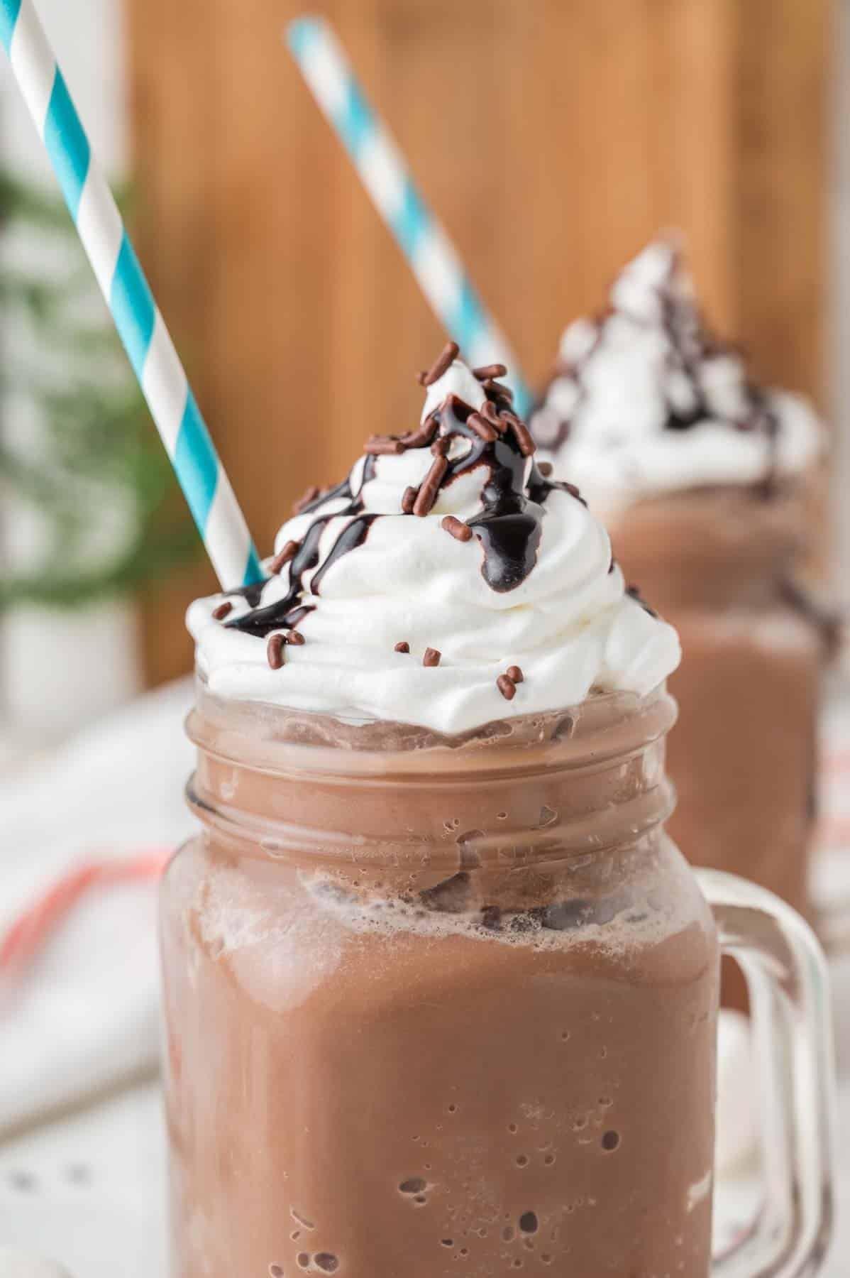 2 frozen hot cocoa drinks in mason jars with blue and white straw