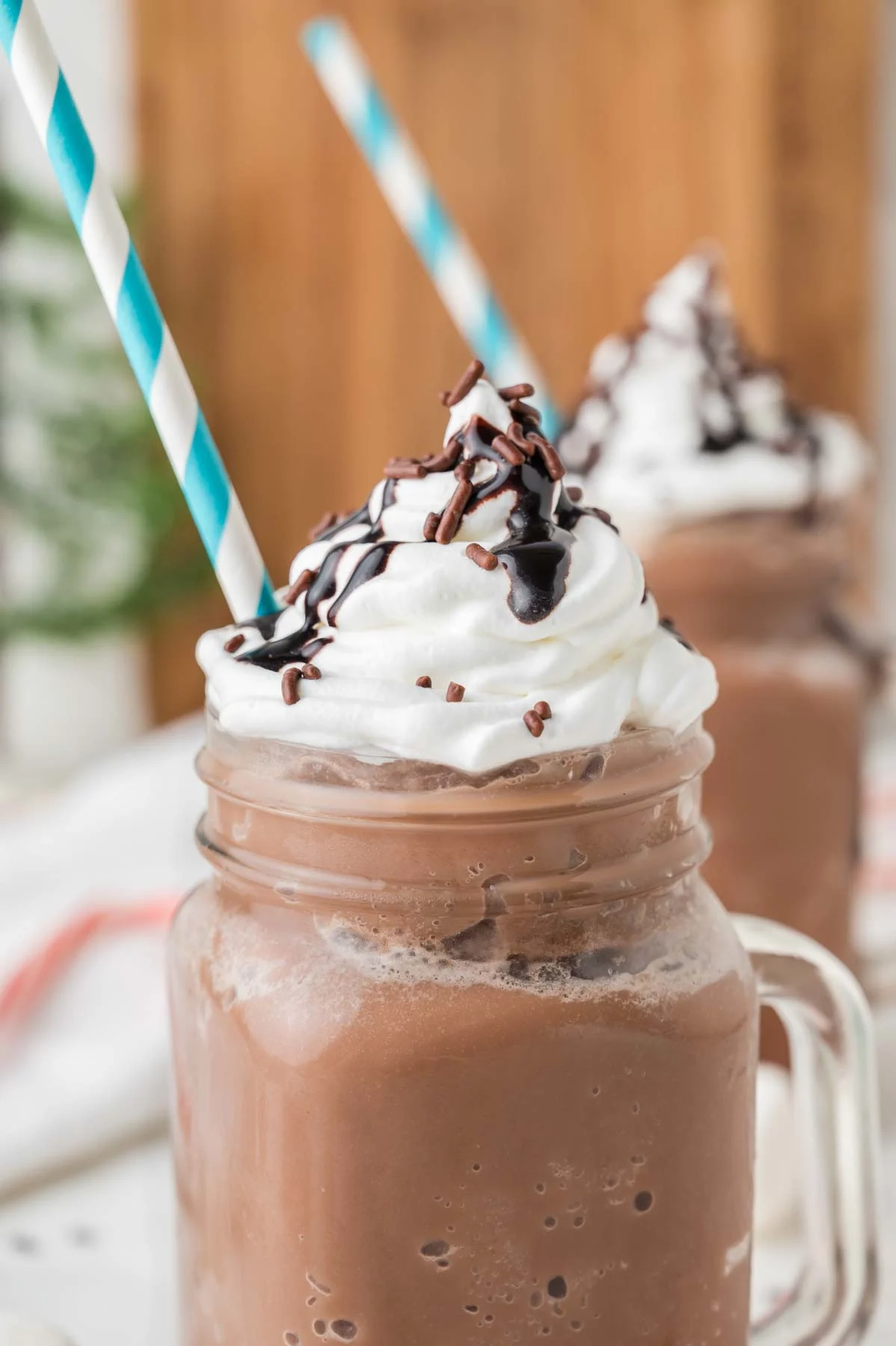 2 frozen hot cocoa drinks in mason jars with blue and white straw