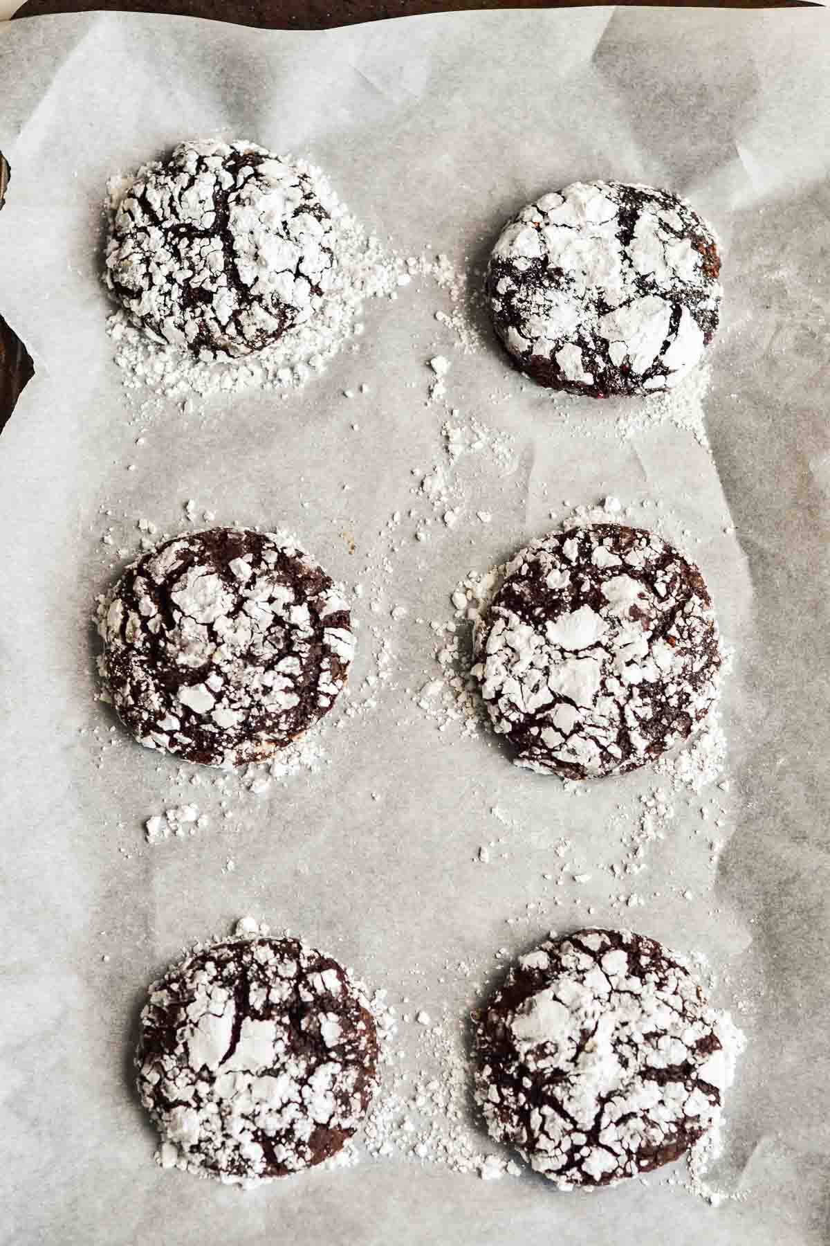 6 raspberry chocolate crinkle cookies on parchment lined baking sheet