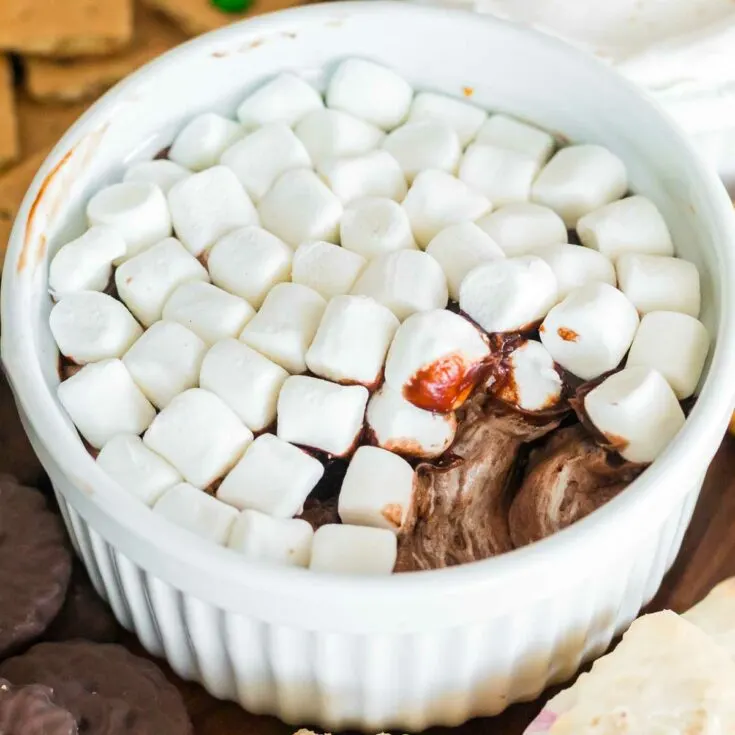 a spoonful taken out of the hot chocolate dip so you can see underneath the marshmallow layer