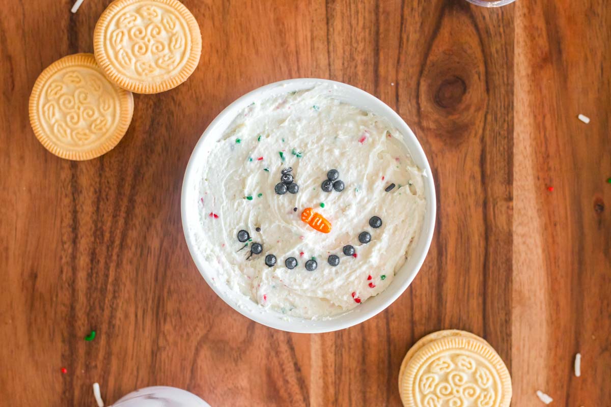 sugar cookie dip in a white ramekin decorated like a snowman face