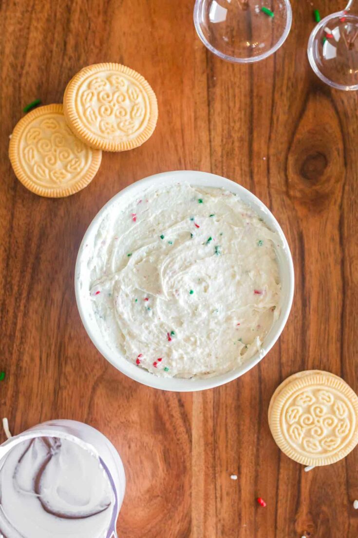 finished sugar cookie dip in white ramekin on wood background with a few golden oreos around it