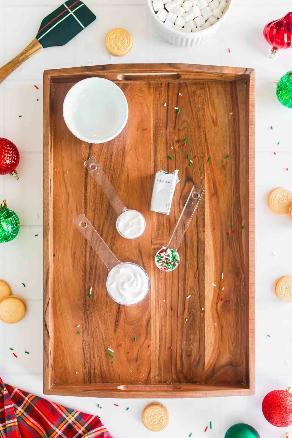 ingredients for sugar cookie dip in individual measuring spoons on wooden serving board