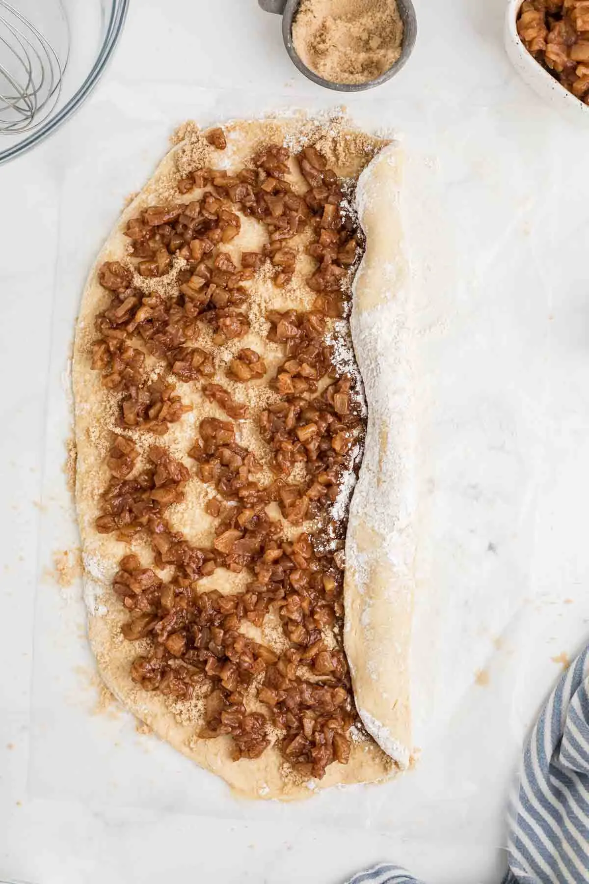 rolling the dough over the apple pie filling.