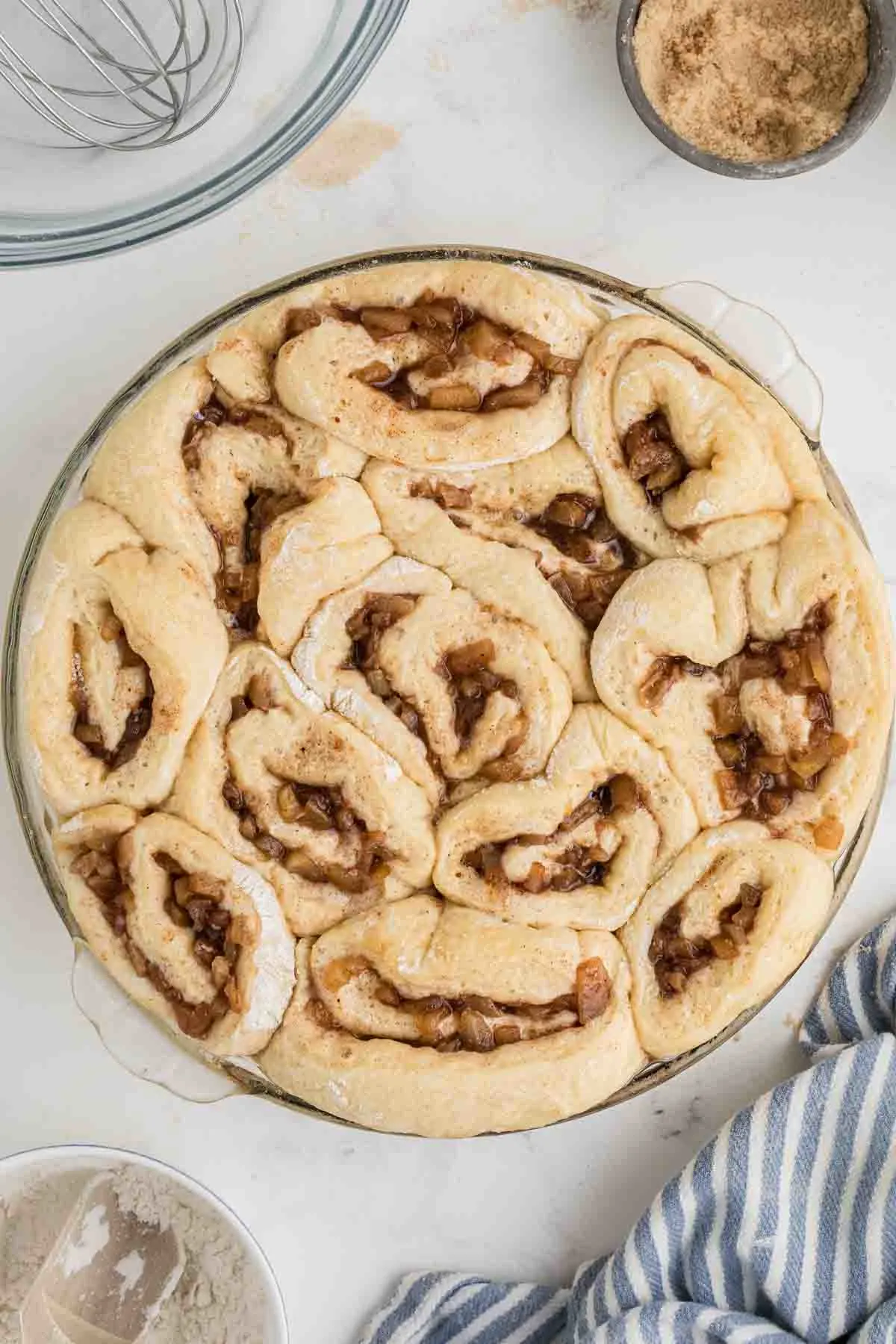 apple pie filled cinnamon rolls in baking dish before baking, after rising.