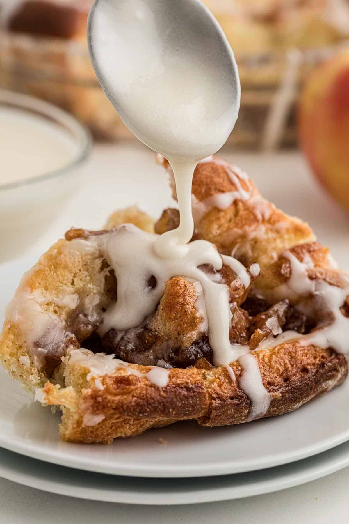 pouring icing over an apple pie cinnamon roll.