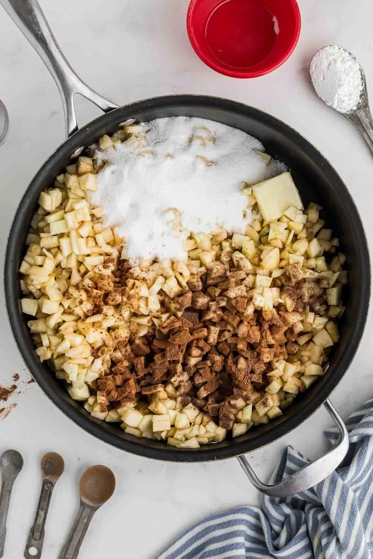 Skillet with chopped apples and spices to make apple pie filling.