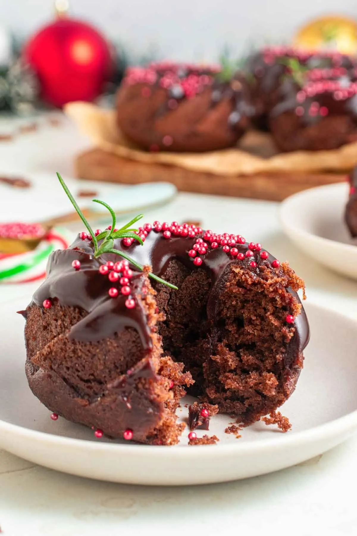 a holiday decorated mini chocolate bundt cake with rosemary and pink sprinkles.