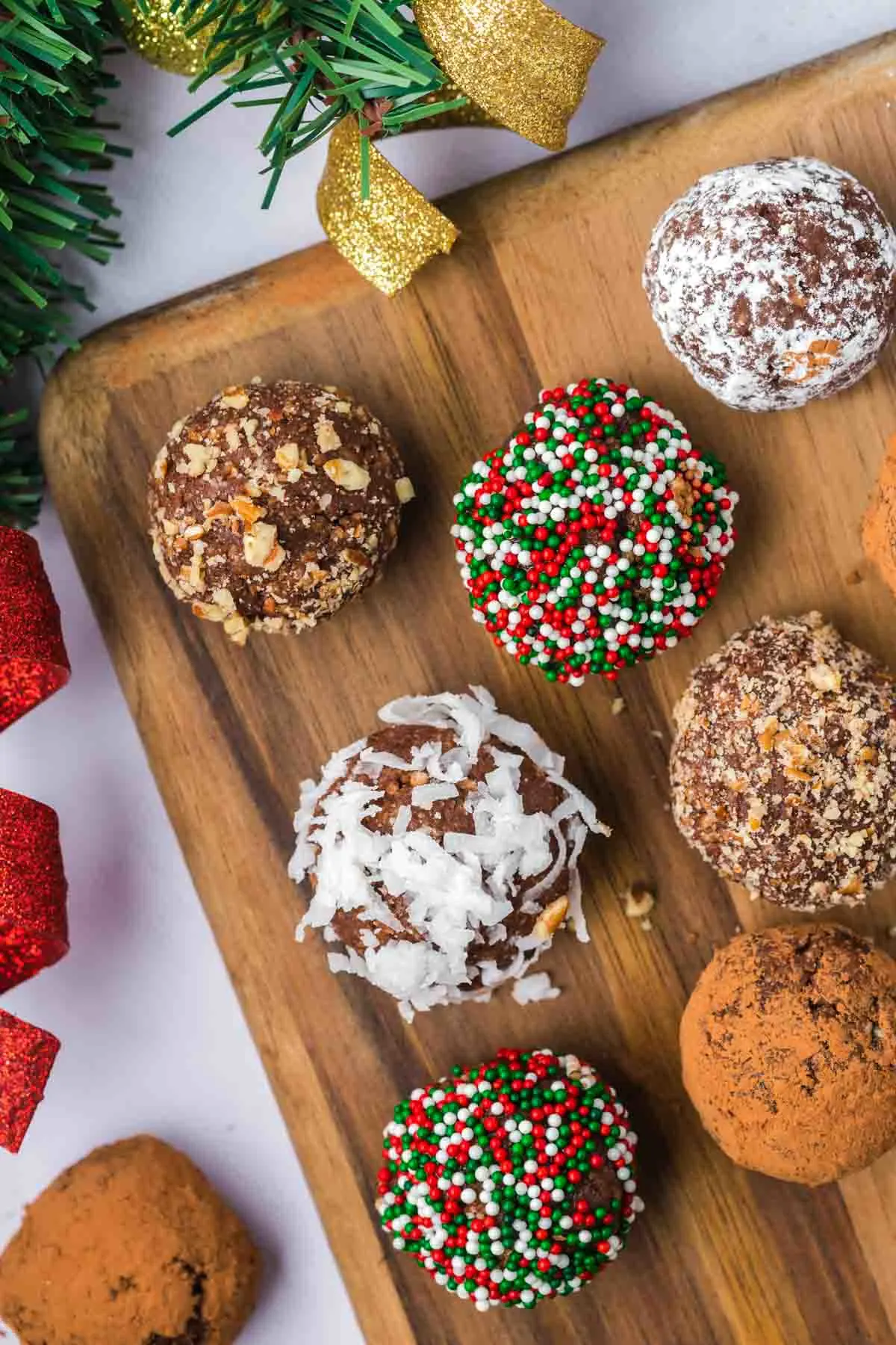 Chocolate Rum Balls with different toppings on a wood serving board.