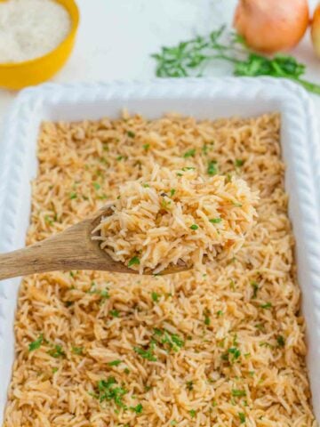 spooning out french onion rice from casserole dish