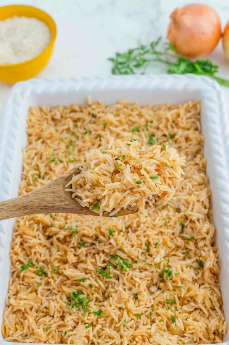 spooning out french onion rice from casserole dish