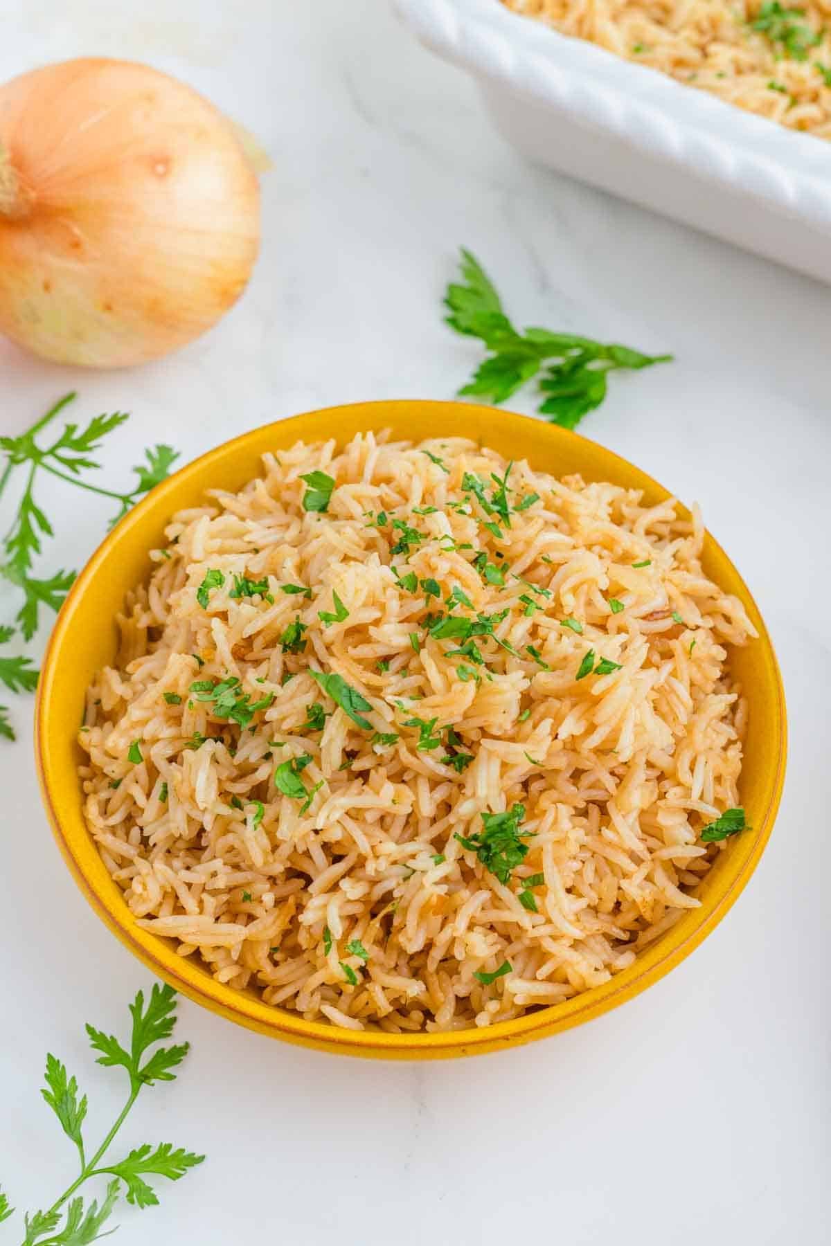 french onion rice in bowl with garnish and whole onion in background